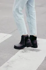 Bota corta de cuero negro con diseño minimalista, cierre lateral metálico y taco bajo cuadrado de 4 cm.
