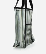 Bolso de playa rectangular de poliéster con rayas verticales en tonos de verde, gris y blanco. Tiene asas de algodón negras y un bolsillo externo.