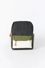 Mochila de pana con diseño de bloques de color. El cuerpo principal es gris oscuro con textura acanalada, un bolsillo frontal superior en verde oliva y un bolsillo frontal inferior en blanco crema con textura acanalada. Los tiradores de cremallera son de color cobre.