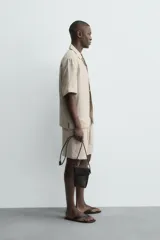 Bermuda de lino color blanco hueso, de corte relajado y tiro medio. Presenta cintura elástica ajustable con cordón, pliegues frontales y bolsillos laterales y trasero.