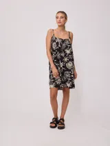 Vestido corto color naranja con estampado de motivos playeros en blanco, de breteles finos y corte suelto.