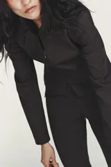 Cazadora entallada de color gris oscuro, con cuello solapa, manga larga y cierre frontal con cremallera de doble cursor. Presenta costuras marcadas y forro interior.