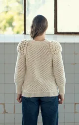 Sweater tejido a crochet color crudo, con cuello redondo, mangas largas y hombros abullonados.