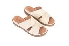 Sandalias Lota de cuero off-white, con tiras cruzadas texturizadas y suela de poliuretano color marrón con plataforma baja.