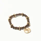 Pulsera elástica de cuentas facetadas color marrón con detalles dorados y dije circular dorado.