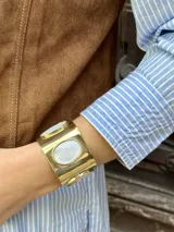 Brazalete dorado con tres incrustaciones ovaladas de nácar, diseño ajustable.