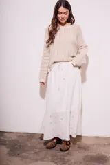 Falda larga blanca de viscosa y lino, con cintura elastizada y cordón ajustable. Presenta bordado calado con motivos florales en el ruedo.