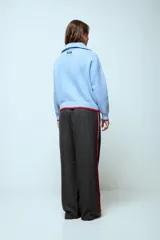 Sweater de punto color celeste con cuello polo y cierre frontal parcial. Presenta detalles de terminación en color rojo en el cuello, puños y ruedo.