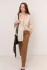 Chaqueta beige de lino con mangas 3/4, cuello mao y detalles de costuras decorativas oscuras en contraste.