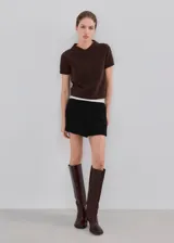 Minifalda negra de tiro medio, con diseño cruzado tipo envolvente (wrap) en el frente.