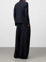 Pantalón sastre de pierna ancha en color azul marino, con pliegues delanteros y cierre cruzado. Incluye bolsillos laterales y bolsillos de vivo en la parte posterior, confeccionado en una mezcla de poliéster, lana merino y viscosa.