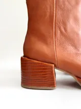Bota de caña media color óxido, confeccionada en cuero, con plataforma y taco cuadrado texturizado, punta cuadrada y cierre lateral.