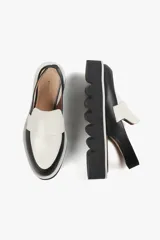 Mocasín slingback de cuero negro con detalle blanco en el empeine y base con plataforma dentada.