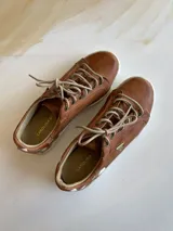 Championes de cuero color terra con diseño pintado a mano en el talón, cordones claros y suela de goma blanca.