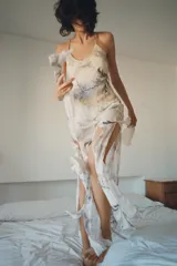 Vestido midi de viscosa con estampado floral y geométrico en tonos neutros. Presenta escote redondo, tirantes finos cruzados en la espalda con ajuste de lazada y forro interior.