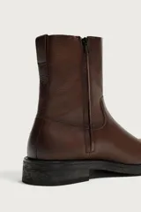 Bota de piel color marrón con cierre de cremallera lateral, horma cuadrada y suela con ligero tacón.