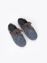 Zapato destalonado tipo slide color azul con diseño de micromotivo geomético, combinado con detalles de cordones y apliques de cuero marrón, ojales metálicos y un pasador metálico decorativo en el lateral.
