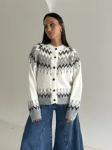 Cardigan de punto con diseño jacquard de inspiración nórdica, en tonos blanco, gris y marrón. Presenta cuello redondo, cierre frontal con botones y mangas largas con puños acanalados.