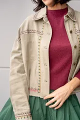 Campera de jean color beige con bordados florales en tonos rosa, verde y amarillo.