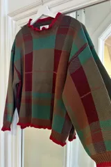 Sweater de punto con diseño de cuadros escoceses en escala XL, en tonos azul, verde y marrón. Presenta cuello redondo y puños con detalle de volados en color fucsia, con un corte oversize.