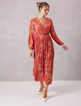 Vestido midi de gasa estampada con diseño floral, escote en V cruzado, cintura elastizada con lazo de ajuste y mangas largas con puños fruncidos. Incluye forro interno a tono.