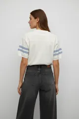 Remera de algodón de corte holgado con cuello redondo y mangas cortas. Presenta un diseño de estilo deportivo con franjas blancas en las mangas y una estampa frontal con temática de béisbol y un tigre.