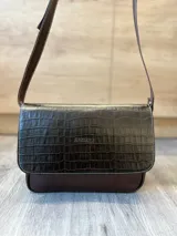 Cartera bandolera de cuero vacuno color bordó, con solapa frontal de textura símil cocodrilo y detalles de costuras pespunteadas en blanco. Cuenta con correa ajustable y cierre superior.