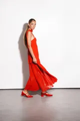 Vestido largo negro confeccionado en crepé y gasa, de corte al cuerpo con escote recto, tiritas finas y falda larga semitransparente con tajo lateral pronunciado. Incluye accesorio tipo corbatín a juego.