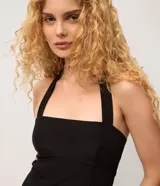 Vestido corto sin mangas en crepé color negro, con escote halter y pollera levemente evasé.
