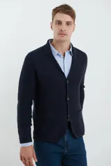 Cardigan tejido color azul marino, con cuello y solapa, cierre frontal de botones y bolsillos delanteros. Presenta un tejido de punto con textura.
