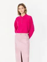 Sweater de lana color fucsia, con cuello tipo polo, mangas largas y botones.