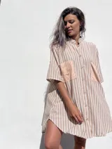 Camisola de corte oversize con estampado de rayas verticales en tonos beige y blanco. Presenta cuello mao, cierre frontal con botones y dos bolsillos delanteros en contraste de material tipo gamuza.