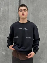 Buzo negro de corte holgado con cuello redondo y puños acanalados. Estampado frontal con la palabra "OSTEN" y la frase "NOT WHERE YOU'RE FROM A MINDSET OF BECOMING" en color blanco.