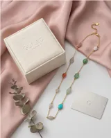 Collar de cadena fina con baño de oro, adornado con piedras naturales de diversos colores y formas ovaladas distribuidas a lo largo de la pieza.