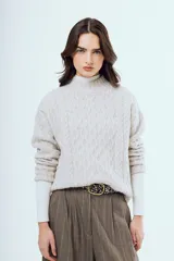 Sweater tejido negro de silueta relajada, con cuello alto y textura trenzada.