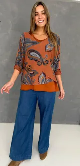 Blusa de algodón con diseño de doble capa, compuesta por una musculosa base y una capa superior de tejido liviano con estampado paisley en tonos naranja, celeste y marrón. Presenta un corte oversize y mangas tres cuartos.