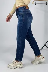 Jean estilo mom de tiro alto, confeccionado en denim azul con lavado clásico. Presenta corte recto y holgado, con cierre y botón frontal, y bolsillos laterales y traseros.