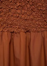 Vestido midi de diseño combinado con cuerpo entallado de textura arrugada y falda fluida. Presenta cuello perkins, diseño sin mangas y espalda abierta con cierre de botones.