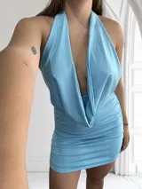Vestido corto celeste con escote halter y espalda descubierta. Diseño drapeado con frunces en la falda.