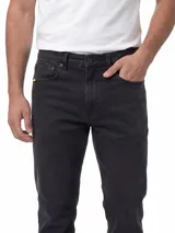 Jeans de corte slim fit en color negro, confeccionados en tejido denim elástico. Presentan diseño clásico de cinco bolsillos, cierre de cremallera con botón personalizado, remaches metálicos con logo y parche de cuero con marca en la parte trasera.