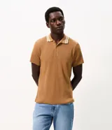 Remera polo marrón de tejido de tricot texturizado, de manga corta, con cuello polo abotonado y detalles de rayas blancas en el cuello.