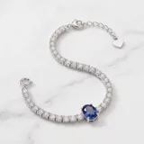 Pulsera de plata 925 tipo tenis, con una hilera de circonias blancas y un dije central de circonia azul en forma ovalada.