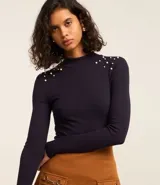 Blusa azul marino de mangas largas, confeccionada en rib con viscosa, cuello alto y perlas artificiales aplicadas en los hombros.