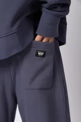 Pantalón de jogging de corte recto y fit relajado, confeccionado en tejido de algodón de color gris azulado. Presenta una caída amplia, cintura elástica y un pequeño logo bordado en la parte superior del muslo.