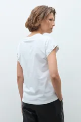 Remera de algodón color blanco, de corte clásico y manga corta, con detalle de strass en el borde de la manga.