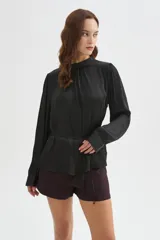 Blusa de poliéster color negro con cuello alto, mangas largas, diseño holgado, detalles de frunces y lazo ajustable en la cintura.