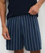 Conjunto de pijama masculino compuesto por una remera de cuello redondo y manga corta en color azul marino liso, y un short con cintura elástica y estampado de rayas verticales en tonos azul y blanco.
