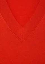 Jersey de punto fino color rojo, con cuello en V y manga larga de diseño recto.