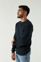 Sweater azul marino de punto con cuello redondo, mangas largas y logo bordado en el pecho.