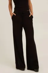 Pantalón de punto acanalado negro de tiro alto, pierna recta y relajada, con cintura elástica y cordón ajustable, y bolsillos laterales.
